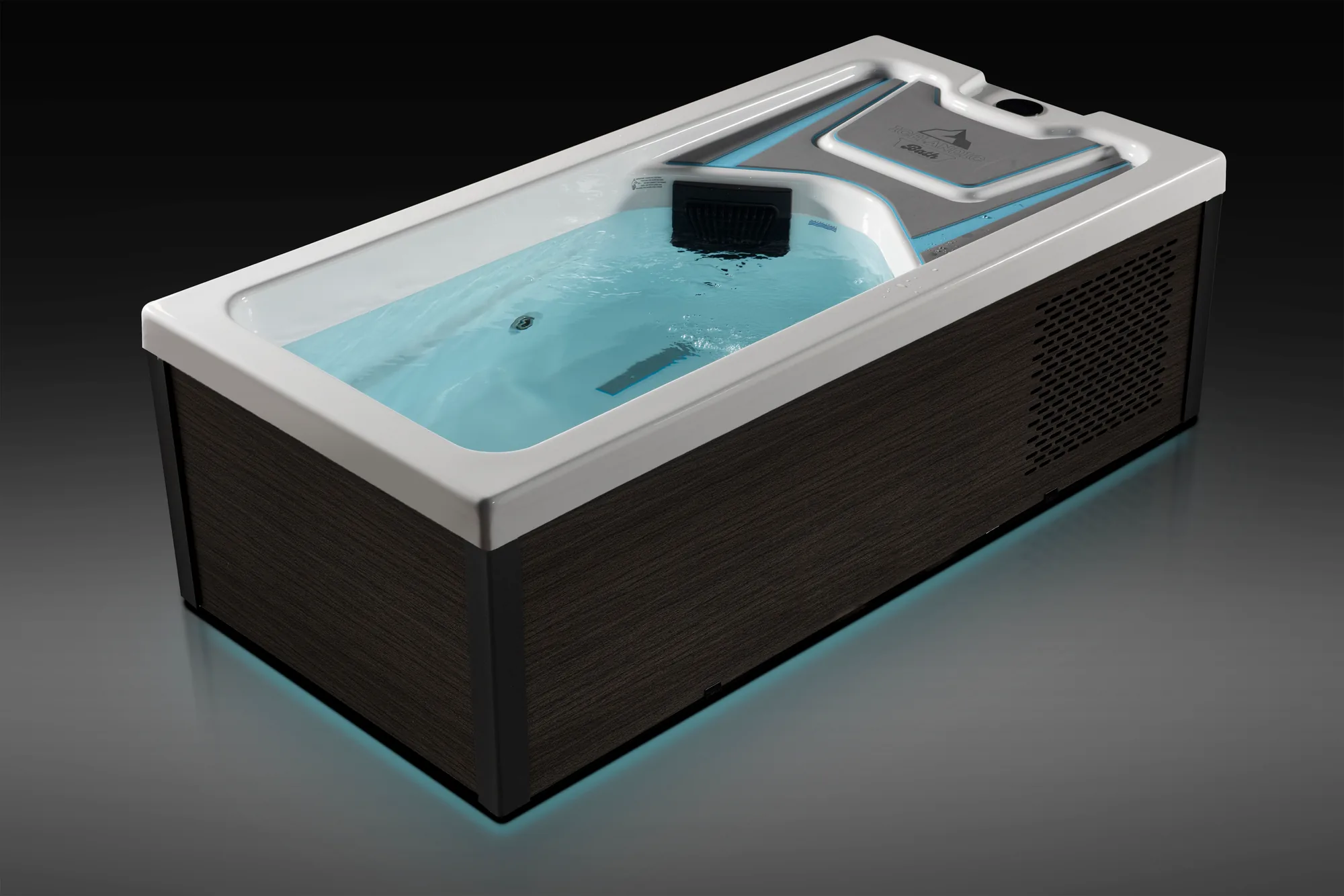 Icelandic Bath schuin van boven, een rechthoekig ijsbad met donkere kast, een hoofdsteun en blauw verlicht water