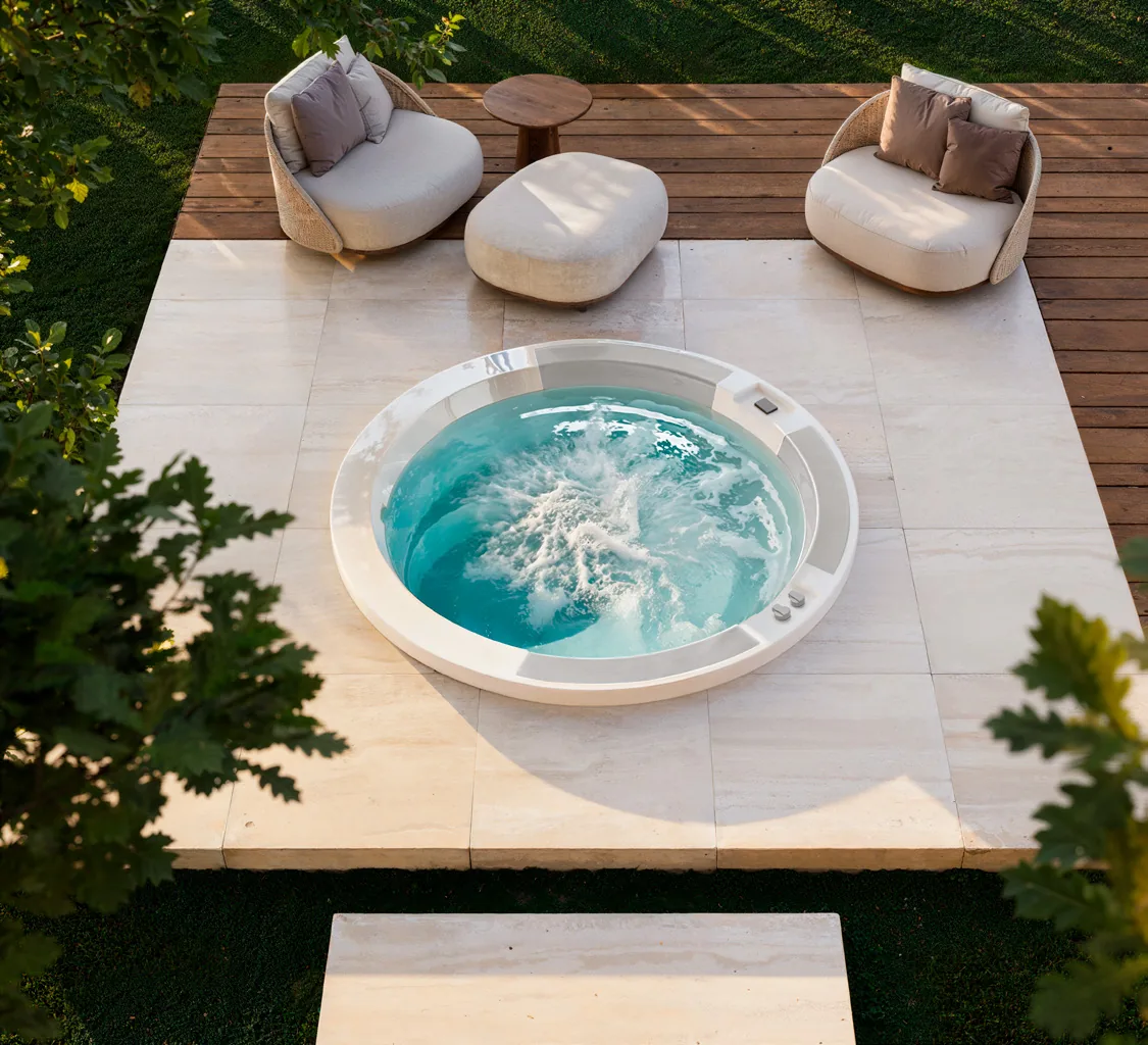 Gruppo Treesse Abyss, een ronde ingebouwde spa met bruisend water in een stenen terras, van bovenaf gezien
