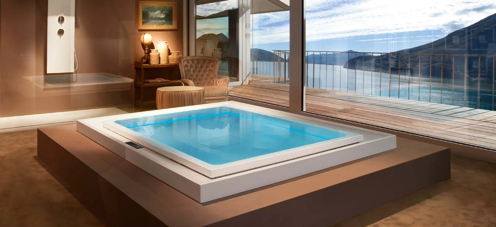 Gruppo Treesse Fusion Spa 230, een rechthoekige witte spa op een houten verhoging in een interieur met uitzicht over een meer