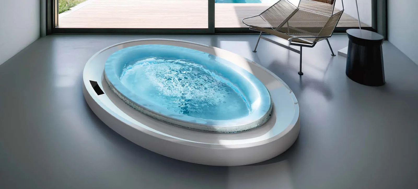 Gruppo Treesse Fusion Spa 231, een ovale witte spa met bruisend water in een lichte ruimte met grijze vloer