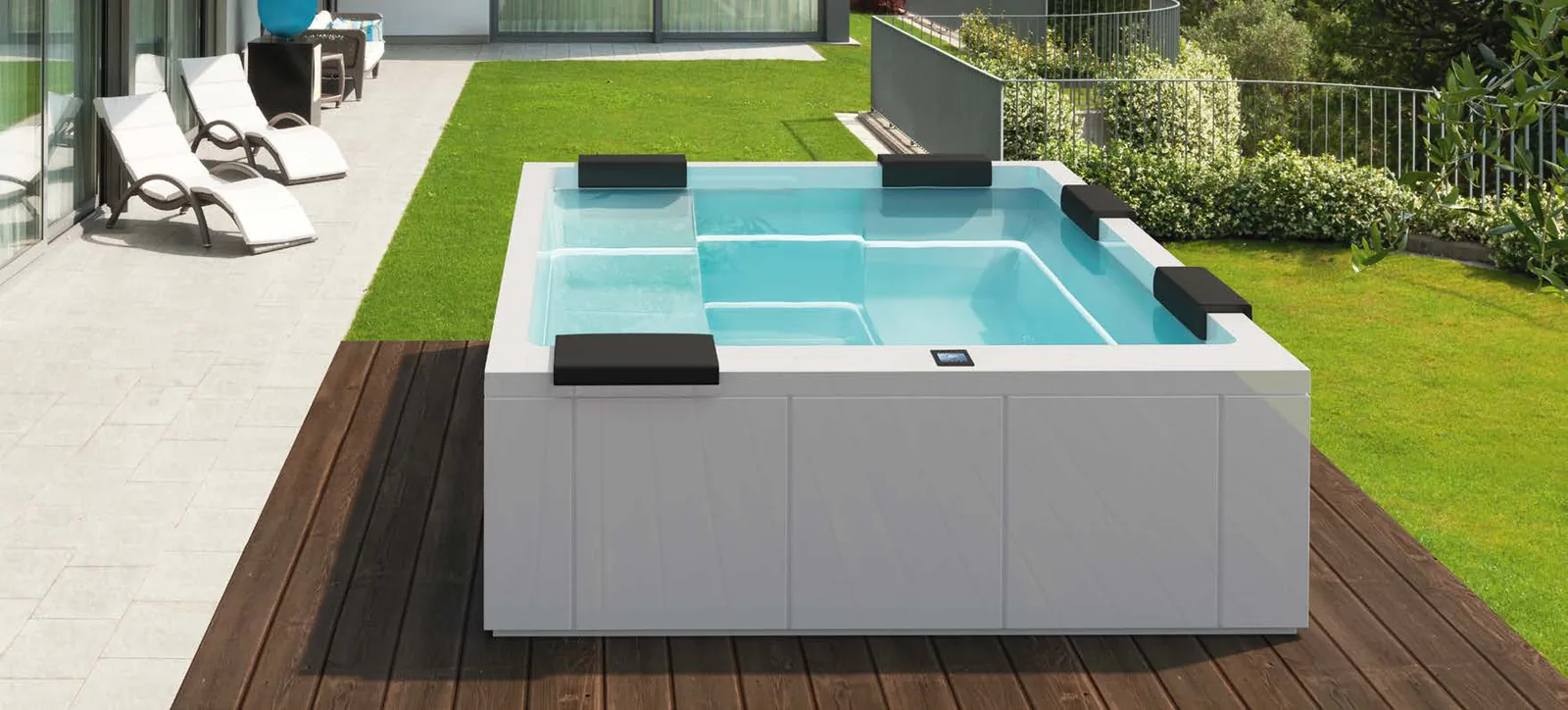 Gruppo Treesse Maya, een rechthoekige vrijstaande spa met witte panelen en vier zwarte hoofdsteunen op een houten vlonder in de tuin