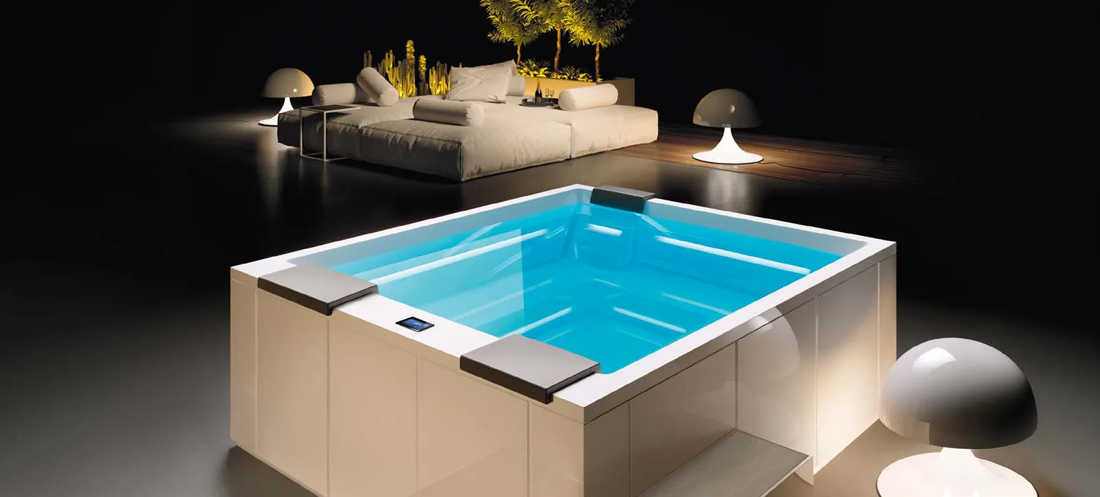Gruppo Treesse Muse GP, een vrijstaande witte spa met hoofdsteunen en bedieningspaneel, bij avond verlicht op een terras